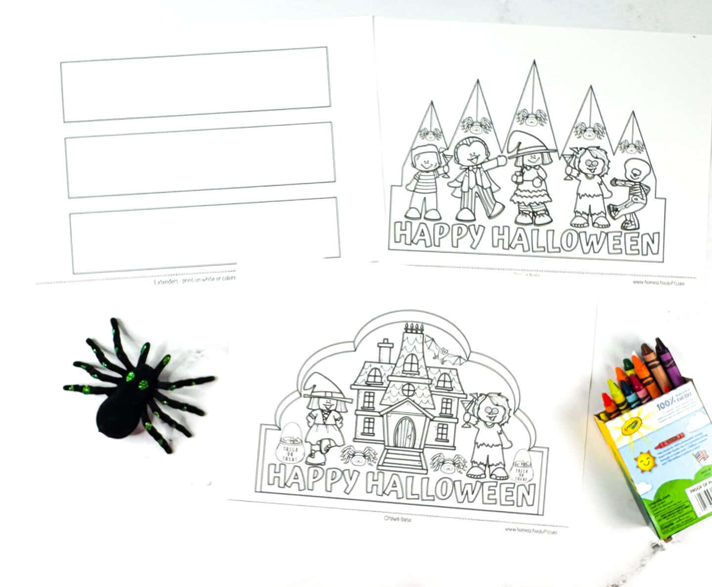 Printable Halloween crown templates in black and white, including trick-or-treat characters and a haunted house, with crayons and a toy spider beside them.