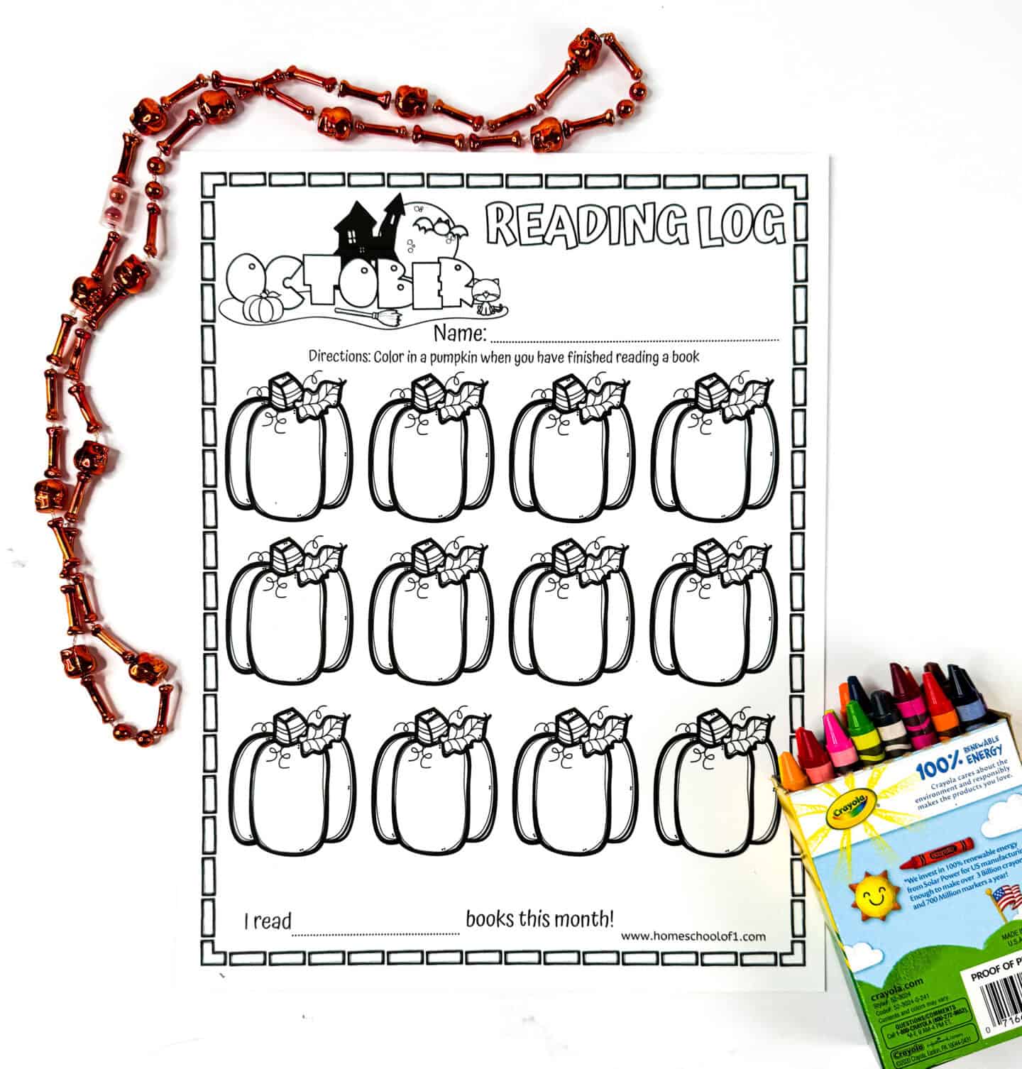 Blank October reading log printable with pumpkin outlines, placed beside an orange Halloween bead necklace and a box of Crayola crayons.


