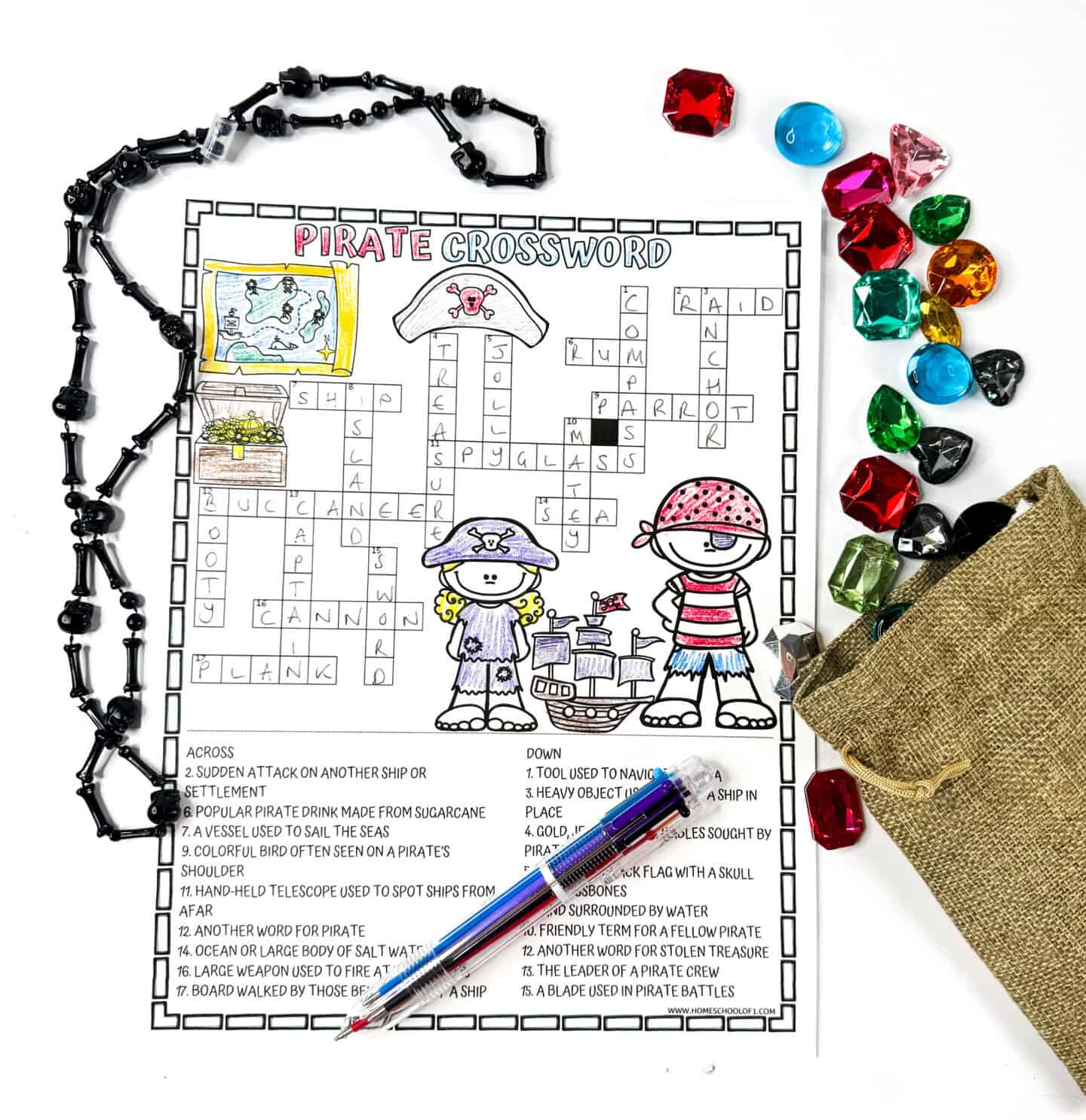 Completed pirate crossword puzzle for kids with colorful gems, pirate beads, and a pen.