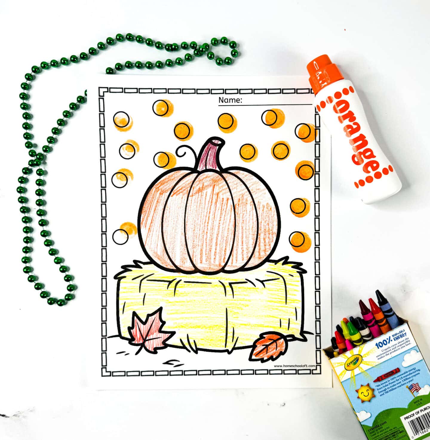 Coloring sheet of a pumpkin sitting on a hay bale with scattered fall leaves and a dotted orange marker background.