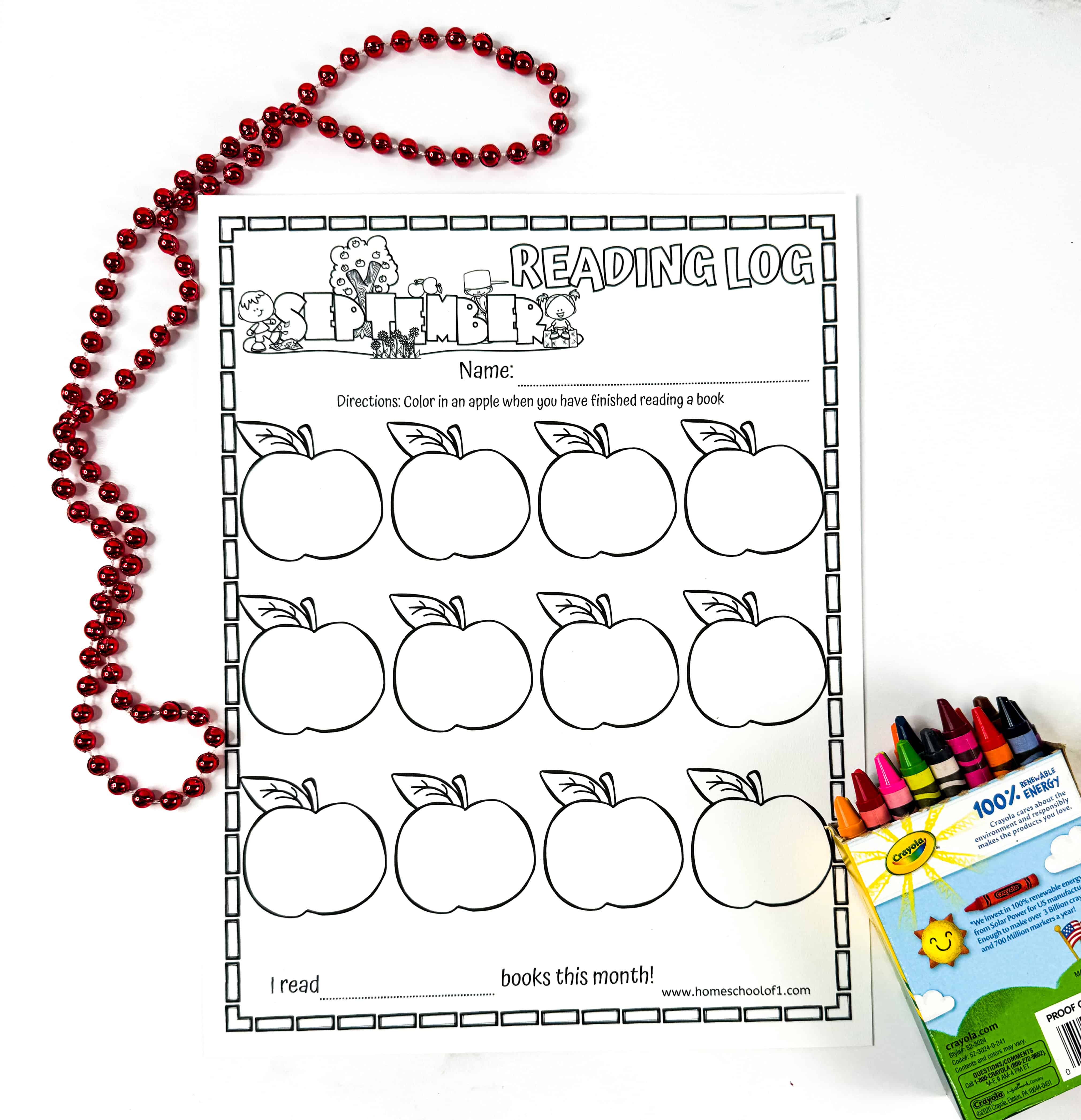 Blank September reading log with apples uncolored, red beaded necklace on the left side, and a box of Crayola crayons on the right.