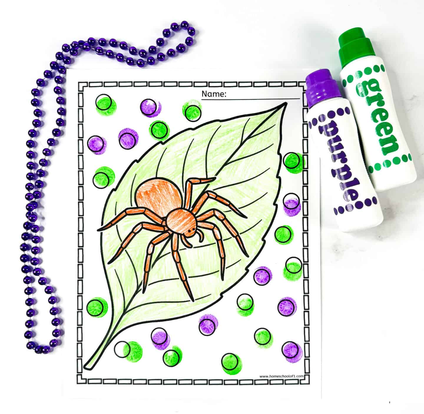 Spider coloring page showing an orange spider on a green leaf, decorated with green and purple dots, placed beside dot markers and a purple bead necklace.