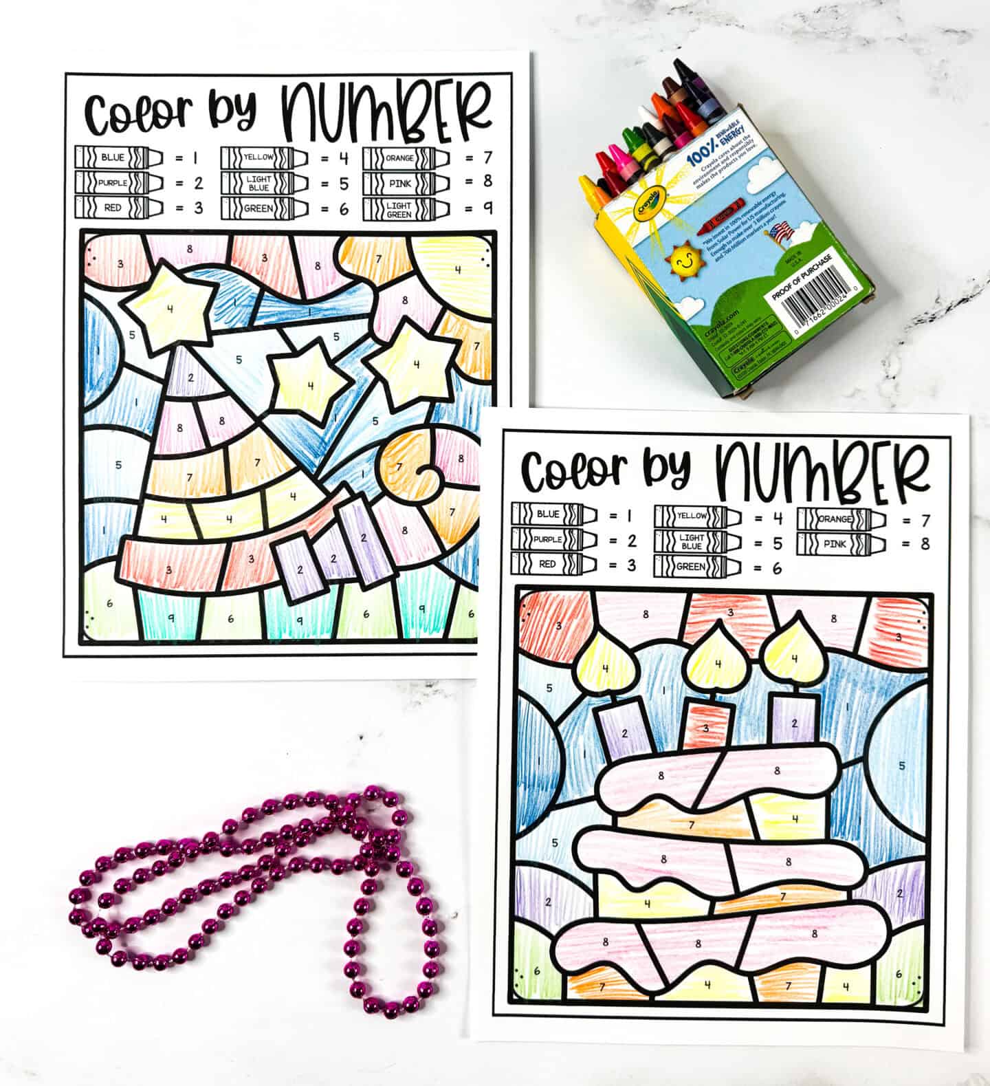 Two birthday color by number worksheets showing a party hat and a birthday cake, colored brightly with crayons, next to pink beads.