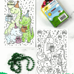 Free printable dinosaur birthday cards to color, shown with crayons and party beads, featuring cheerful dinos with gifts.