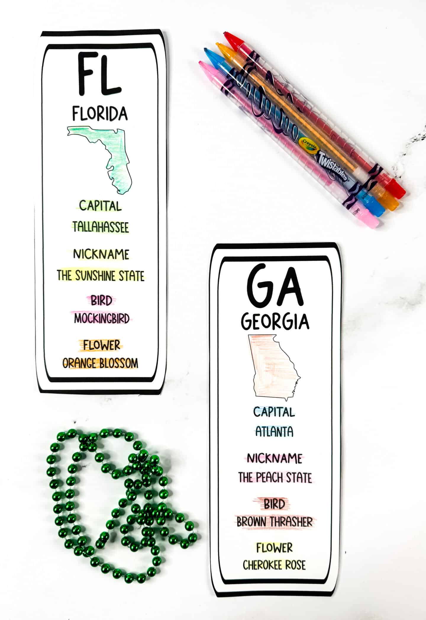 Printable state bookmarks for Florida and Georgia, both hand-colored with crayons. Florida is shaded green with orange and pink accents; Georgia is lightly shaded peach with colored text highlighting state facts. Crayola Twistables and green beads shown.