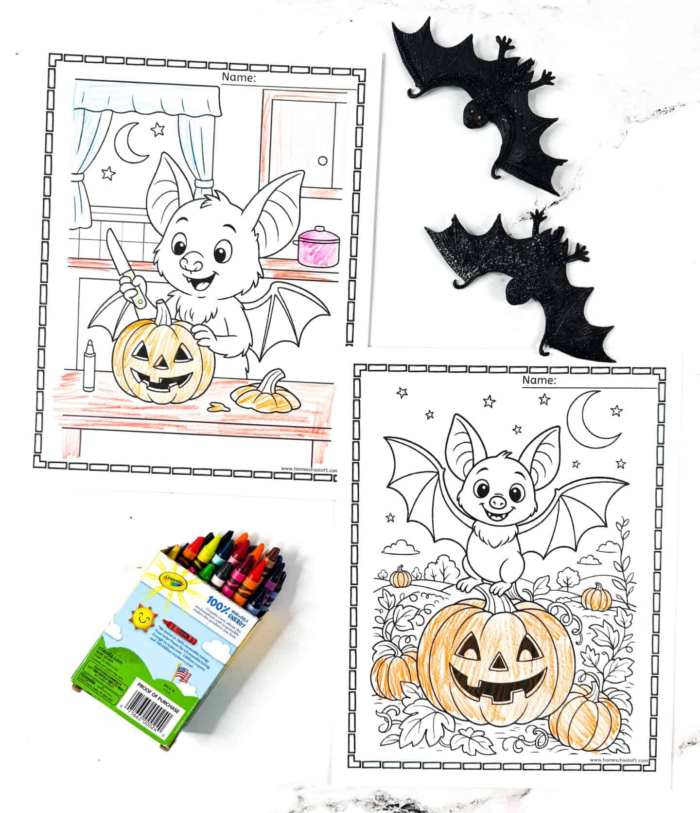 Two Halloween-themed bat coloring pages featuring friendly cartoon bats with jack-o’-lanterns, shown partially colored with crayons, surrounded by plastic bat decorations and a box of Crayola crayons.