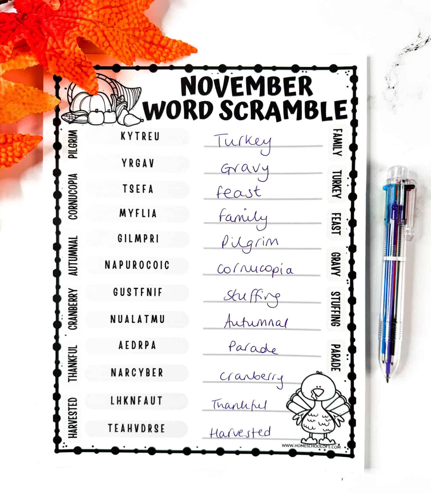 Completed November word scramble worksheet with handwritten answers, surrounded by fall leaves and a multicolor pen.