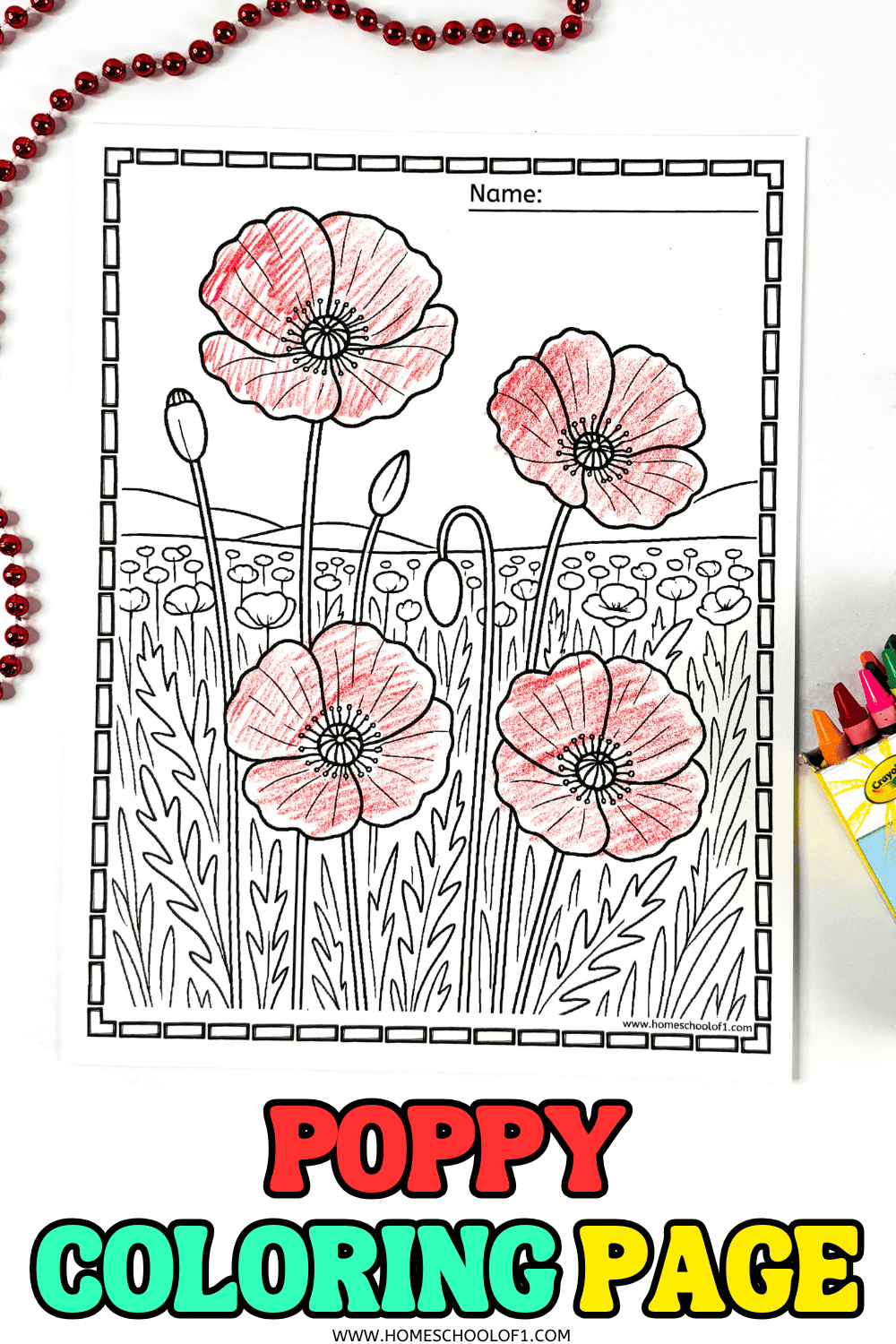 Close-up of a poppy field coloring sheet surrounded by red beads and crayons.