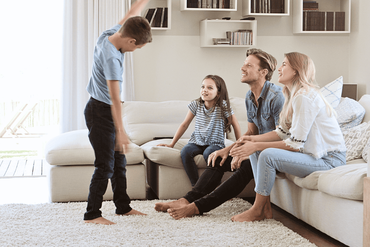 Family playing charades together at home with kids acting out a game and parents guessing
