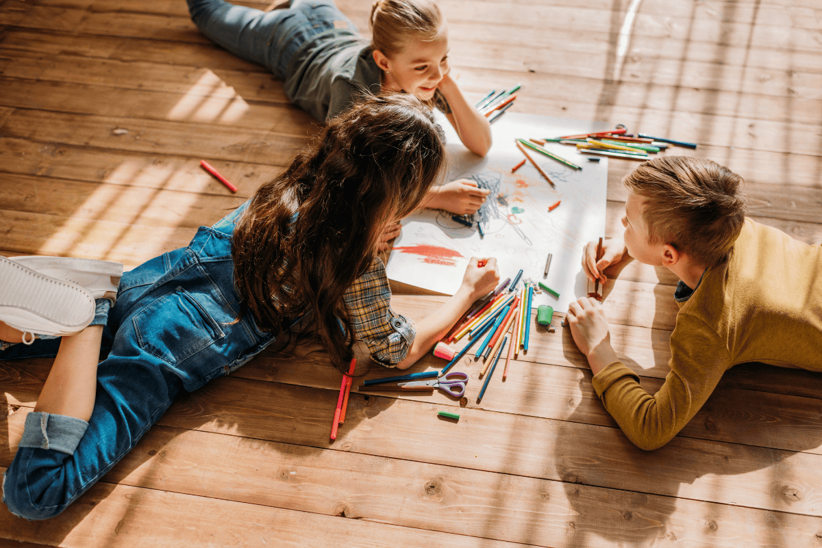 Kids drawing together on the floor with colored pencils during a creative game